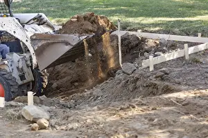 Agricultural Machinery Use Drucke: Small bulldozer digging in yard for pool installation