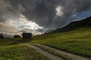 German Mountain Range Views Drucke: Small hut on mountain meadow with path and dramatic cloud sky