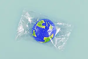 Environmental Awareness Picture Drucke: Small planet earth model wrapped in plastic