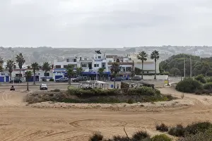 Overcast Sky Scenery Drucke: Small settlement with palm trees and cloudy sky
