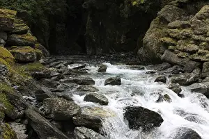 Eroded Canyon Scenery Drucke: Small waterfall flows out of a dark cave