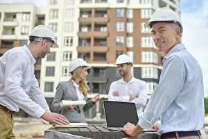 One Person At Work Drucke: Smiling contented middle-aged engineer posing for the camera with his colleagues on the background