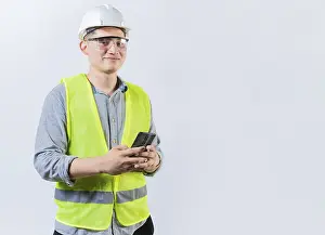 Young Engineer Drucke: Smiling engineer holding phone looking at camera