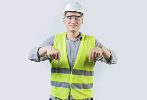 Construction Worker Portrait Drucke: Smiling engineer pointing advertising down isolated