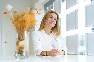 Middle Aged Woman Drucke: Smiling estate agent taking notes while looking at camera working in the office