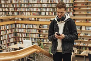 Library Study Space Drucke: Smiling guy with a smartphone in a library