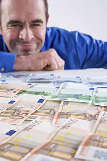 Euro Banknote Drucke: Smiling man looking a bank notes
