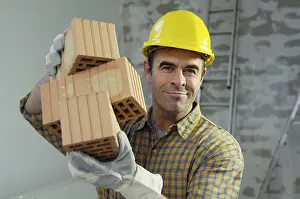 Construction Worker Drucke: Smiling workman holding bricks