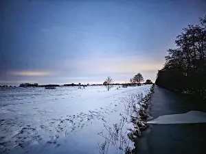 European Winter Landscapes Drucke: Snowy field and river at sunset