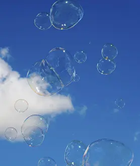 Deserted Beach Scenes Drucke: Soap bubbles float in front of a clear blue sky with a small white cloud