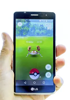 Drucke von Sofia, Bulgarien - 23. Juli 2016: Ein Mann hält in der Hand ein Mobiltelefon, auf dem das Bildschirm Pokémon Go eine erweiterte Realität-Mobil-Spiel zeigt. Isoliert auf einem weißen Hintergrund Sofia Drucke: Sofia, Bulgarien - 23. Juli