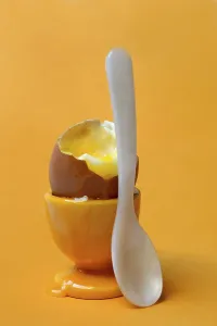 Plain Yellow Background Drucke: Soft boiled breakfast egg in egg cup with spoon