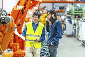 Metal Fabrication Technology Drucke: Software engineer explaining to controlling robotic welding process to welder in factory