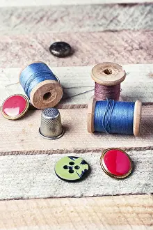 Wooden Background Drucke: Spools of thread and various buttons on wooden background