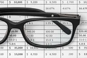 Analyzing Financial Data Drucke: Detail of a spreadsheet and glasses on the table in the office