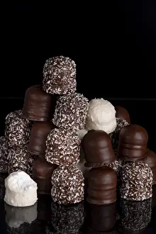 Stacked Desserts Drucke: A stack of different chocolate kisses on a dark background with a reflection