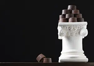 Decorative Food Still Life Drucke: Stack of fine artisan chocolates stacked on white pillar column