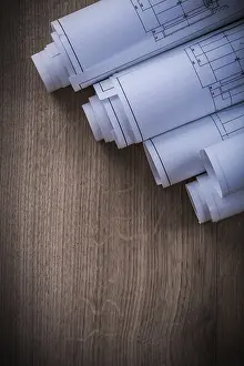 Rolled Blueprints Drucke: Stack of rolled blueprints on wooden background construction concept