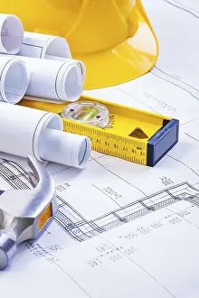 Construction Industry Equipment Drucke: Stack of rolls blueprints level hammer helmet