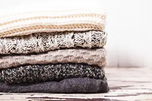 Cozy Knitwear Drucke: Stack warm knitted sweaters in white and gray shades