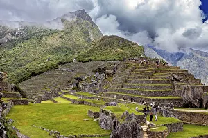 Inca City Peru Drucke: Stepped terraces with ruins against a dramatic mountain backdrop full of clouds