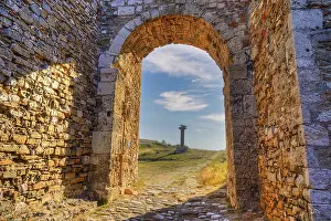 Historic Building Structure Drucke: Stone arch with view of a path and ancient column in the background