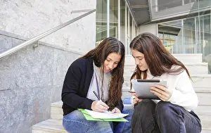 Young People Studying Together Drucke: Two students sit on steps outside
