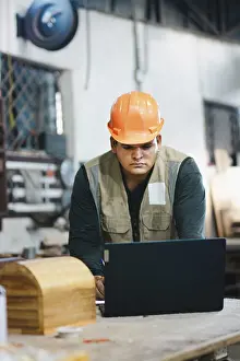 Woodworking Profession Drucke: Successful worker using a computer in the carpentry workshop