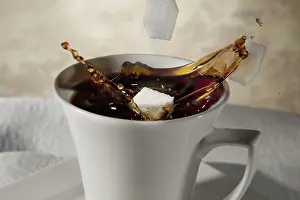 Studio Shot Of Coffee Cup Drucke: Sugar cubes falling into a cup of coffee