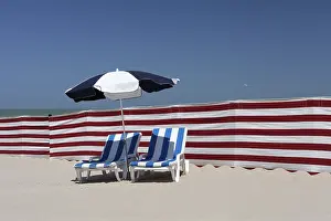 European Vacation Spots Drucke: Two empty sun-beds behind a windbreak