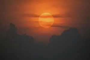 Atmospheric Evening Mood Drucke: Sun disk through the clouds at sunset above the horizon