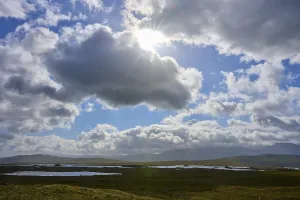 Deserted Lake In Scotland Drucke: Sun rays break through dramatic clouds over a vast landscape with lakes
