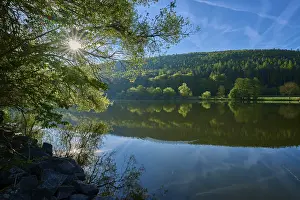 Historic Fortification Germany Europe Drucke: Sun rays through the trees are reflected in the quiet river under a clear sky