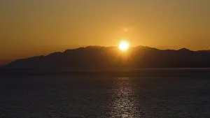 Drucke von Die Sonne untergeht über einem ruhigen Meer, Hintergrund: Berglandschaft, Matala, Südküste, Kreta, Griechische Inseln, Griechenland Matala Drucke: Die Sonne untergeht über einem ruhigen Meer, Hintergrund im Hintergrund.