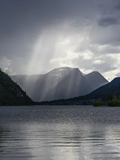 Bilder Datiert 18. Mai 2024: Sonnenschein fällt von Gewitterwolken über den Grundlsee.