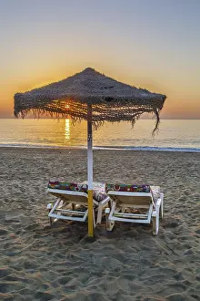 Uninhabited Beach At Sundown Drucke: Sunbed and umbrella on the sunset background