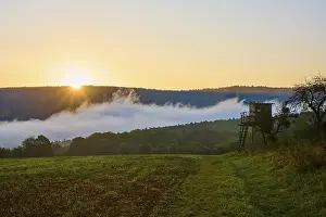 Bavaria Sunrise Drucke: A sunrise over a field with a raised hide