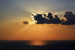 Santorini Sunset Drucke: Sunset behind clouds at the sea