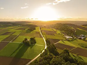 Evening Sun In The Black Forest Drucke: Sunset over green fields and trees glowing in the warm light of the setting sun