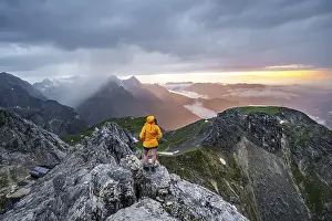 Cloudy Sky Over Mountains Drucke: Sunset, hiker looking at mountains and peaks under dramatic clouds