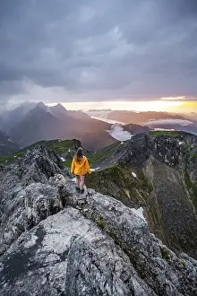 Hiker In The Alps Drucke: Sunset, hiker looking at mountains and peaks under dramatic clouds