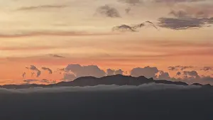 Evening Sun Africa Drucke: A sunset with orange sky and mountains in the background