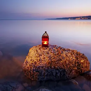 Rocky Coast Sunset Drucke: Sunset on the rocky coast with red lantern
