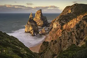 Portuguese Coastal Scene Drucke: Sunset on sandy beach and cliff with rocks