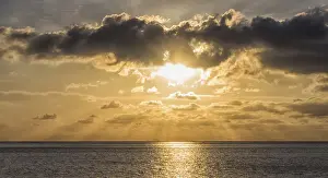 Sunset Over The Sea Drucke: Sunset over the sea with the sun rays through the clouds