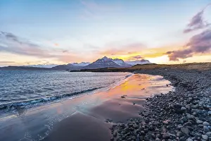 Evening Light On Water Body Drucke: Sunset over snow-capped mountains