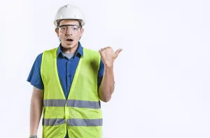 Young Engineer Drucke: Surprised young engineer pointing side advertising space isolated