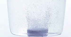 Tablets Dissolving In Water Drucke: Tablets Falling and Dissolving into a Glass of Water against White Background