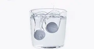Full Body Length Tablet Drop Drucke: Tablets Falling and Dissolving into a Glass of Water against White Background