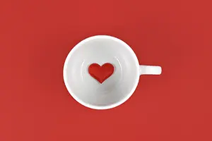 Love Concept Photo Drucke: Tea cup with single heart inside on red background